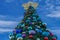 Decorated Christmas tree on lightblue cloudy background at Seaworld.