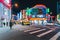 Decorated Colorful lights on buildings and advertisement boards with traffic and people walking on crosswalk in the night.