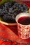 Decorated cup with red stum and grapes near in a clay bowl