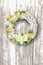 Decorated elegant Easter wreath with eggs flowers and leafs - on rustic wooden background