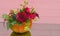 Decorated Halloween pumpkin with flowers and leaves on pink wood