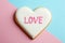 Decorated heart shaped cookie with word LOVE on color background, top view
