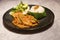 Decorated platter dinner with creamy chicken and salad served in a black plate on a wooden table in touristic visit in Bali