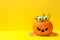 Decorated pumpkin with candy eyes on yellow background