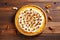 Decorated pumpkin tart with nuts on a wooden background, top view