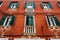 A decorated red house facade with green shutters on the windows in Rovinj, Croatia.