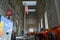 Decorated with red kiosks large corridor of the Milan Central railway station and people walking.