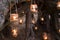 Decorated romantic place for a date with jars full of candles hunging on tree and standing on a sand. Copy Space