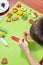 Decorating cinnamon cookies by a child. The boy`s hands form a face of colored icing squeezed out of tubes. Unaddressed biscuits i