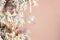 Decoration on Christmas tree - light violet birds and glassy ball on snowy spruce against pink background. Closeup