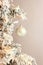 Decoration on Christmas tree - white birds and silver ball on snowy spruce on light gray background. Closeup