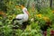 Decoration for the flower garden, the bird stork stands among the flowers.