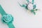 Decoration on hand in the form of a rose of emerald color, sewn to a satin ribbon. Near the wedding boutonniere. On a white backgr