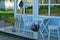 Decorations by the blue wall of the house with a window with chairs and a table with flowers in flowerpots