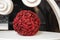 A decorative ball made from red rose sepals stands on a white surface indoors. Interior decoration.