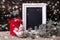 Decorative bird, empty blackboard, candle in lantern and branches fur tree on aged wooden background.