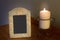 Decorative blank photo frame with lit candle on dresser