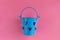 Decorative blue bucket with heart shaped holes on pink background. Festive concept