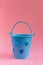 Decorative blue bucket with heart shaped holes on pink background. Festive concept