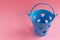Decorative blue bucket with heart shaped holes on pink background. Festive concept