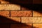 Decorative brick wall with diagonal strip of hard light and dark shadows. Texture stone. Horizontal template of background for