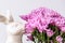 Decorative bunny sniffing a bouquet of pink chrysanthemums, against a white background