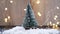 Decorative christmas tree with snow in focus. Defocused christmas lights on background.