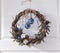 Decorative Christmas wreath made of natural materials, with blue Christmas balls. On the white door. With space