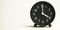 Decorative close-up black analog alarm clock for 4 or 16 o`clock, separate white background with copy space