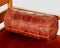 Decorative copper-colored leather bolster cushion on wooden sofa