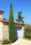 Decorative cypress in front of a provencal stone building.