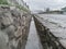 Decorative drain ditch with walls lined with stone boulders near the road, close-up