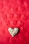 Decorative element in the form of a heart lies on the background of red paper with carved hearts.
