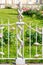 Decorative element of vintage forged white fence with garlands of flowers