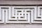 Decorative exterior concrete decoration like pattern or ornament in the form of a labyrinth with a swastika on the outside wall of