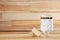 Decorative glass jar with cotton pads and loofahs on table against wooden background