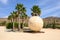 A decorative golden ball between palm trees near Koumbara Beach on Ios Island. Greece