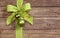 Decorative green bow on a wooden background