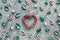 Decorative heart shaped wreath with frosted berries. Geometric Christmas background decorated with holly leaves, red white stripy