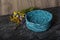 Decorative, large, handmade knitted basket for items in turquoise color. Beside him are wildflowers.