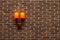 Decorative, neat wall made of brown ceramic bricks and wall lamps with orange shades