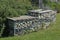 Decorative pebble gabion landscaped with a bench and plants in an urban green space