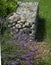 Decorative pebble gabion landscaped with a bench and plants in an urban green space