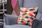 Decorative pillow with multi-colored rhombuses on a gray armchair in the living room