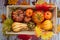 Decorative pumpkins for the autumn holiday are packed in a wooden box with straw. View from above