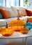 Decorative pumpkins of different sizes and shapes made of colored glass. Stylish Halloween decor. White blurred living