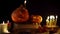 Decorative pumpkins Jack standing on old books in candle light, camera panning