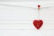 Decorative red heart hanged on a clothespin on a white background.