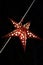 A decorative red star hangs on a metal cable. Decorative lantern in the shape of a star