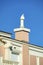 Decorative rooftop with chimney vent and beige or brown stucco exterior with white accent decorations and blue sky